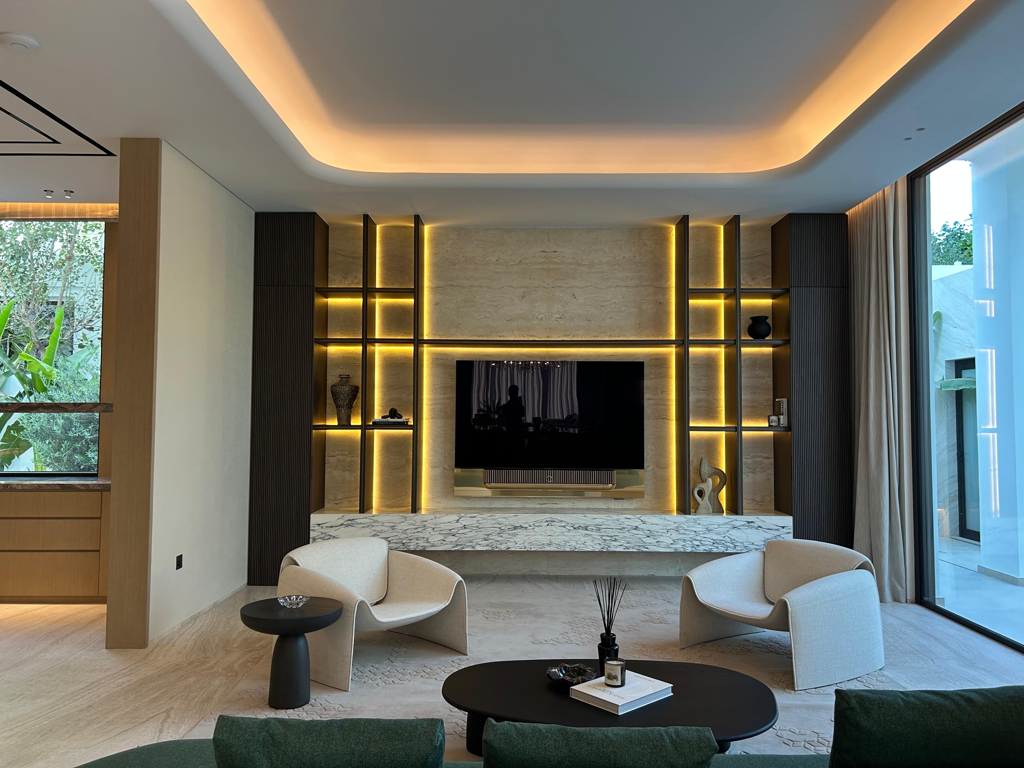 Luxury living room with backlit travertine feature wall and marble console by Mistry Interiors