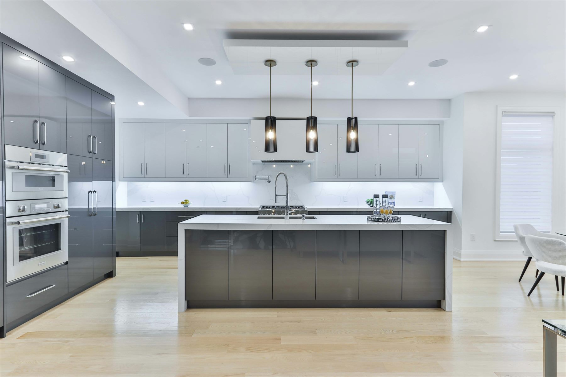 Modern grey kitchen with island, three pendant lights and bespoke cabinetry by Mistry Interiors, Dubai
